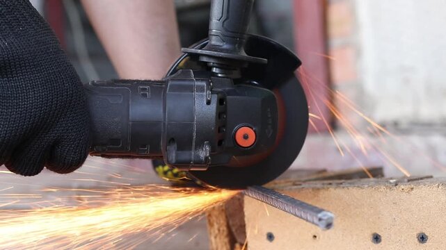 Cordless angle grinder cuts rebar. Sparks fly when cutting rebar with a grinder, construction work close-up. Electric tool for construction and repair work. Grinding machine with metal disc