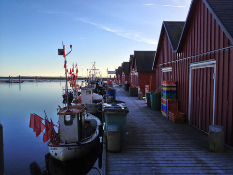 Fishing boats and storage buildings lined along a quiet harbor in the early morning light in the baltic sea in Boltenhagen