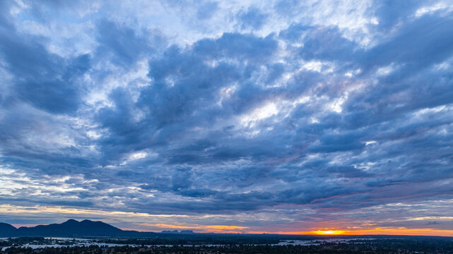 A breathtaking aerial view of Khone Phapheng Waterfall at sunset reveals powerful multi tiered cascades surging through rocky channels, glowing beneath golden light in southern Laos.