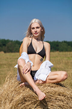 Sexy young woman in a straw hat lies on a haystack