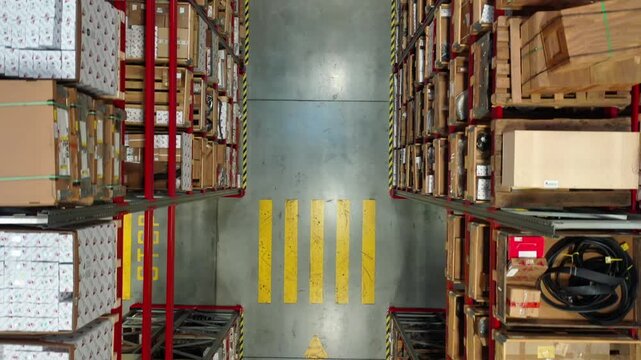 Top down drone moving backward over warehouse aisle
