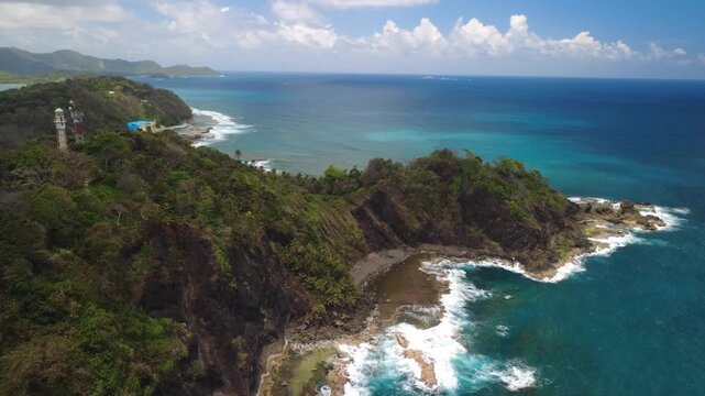 Caribbean Island and lighthouse with wild tropical coastline in Isla Grande, Panama with crystal clear turquoise ocean, steep cliffs, dense jungle vegetation and untouched Caribbean landscape.
