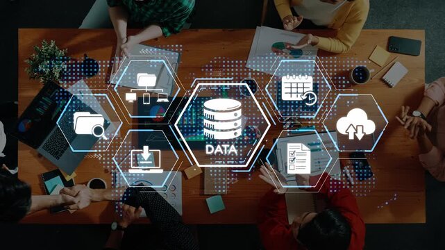 An overhead view of a team collaborating on data management using digital tools in a modern office setting. The image highlights technology integration in business. Raster
