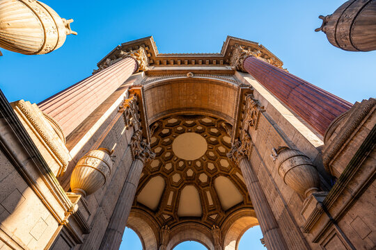 A dramatic low-angle perspective showcases the towering Greco-Roman columns and intricate rotunda of the Palace of Fine Arts against a brilliant blue San Francisco sky.