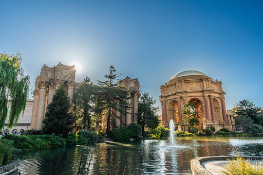 A serene morning view of the Palace of Fine Arts rotunda reflecting in the tranquil lagoon under a clear San Francisco sky.