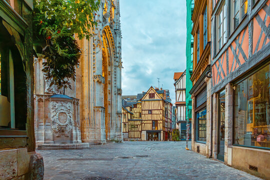 Historic street in Rouen old town with gothic cathedral facade and half timbered houses at sunrise, Normandy, France. French city. Historic architecture and travel destination in Europe