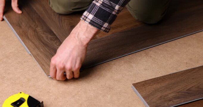 man installing new vinyl tile wood texture flooring in a herringbone pattern