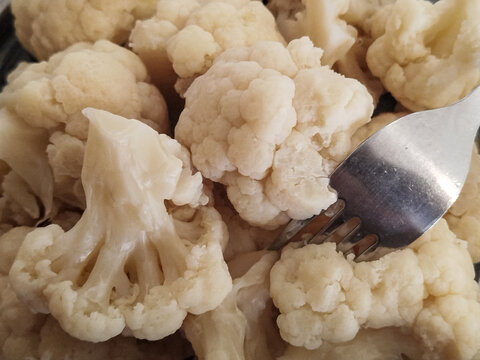 Primer plano de ramilletes de coliflor cocida cubiertos con una salsa cremosa tipo bechamel