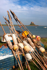 The castle and harbour from the Common, Lindisfarne, Holy Island, Northumberland, UK, with fishing floats and an upturned boat in the foreground © Will Perrett