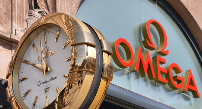 Prague, Czech Republic &ndash; March 22, 2026: Omega luxury watch brand sign and street clock mounted on building facade in Prague city center with illuminated branding, retail storefront