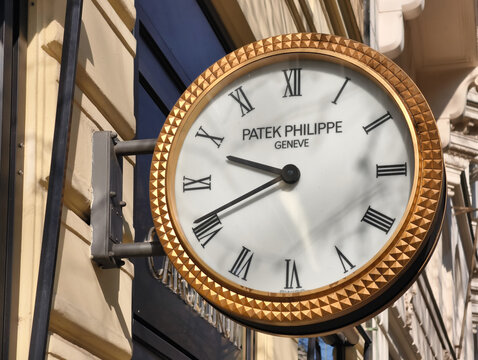 Prague, Czech Republic - March 22, 2026: Patek Philippe Geneve branded outdoor wall clock with a gold hobnail bezel and Roman numeral dial in Prague.