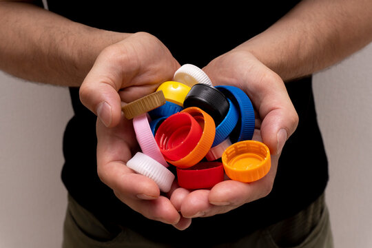 Closeup at caucasian hands full of colorful plastic bottle cups,