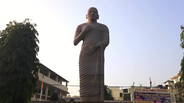 Standing Buddha statue in outdoor setting in India. Symbol of peace, meditation, and spirituality. Buddhist sculpture in temple or public area representing calmness, enlightenment, Bodh Gaya, Bihar.
