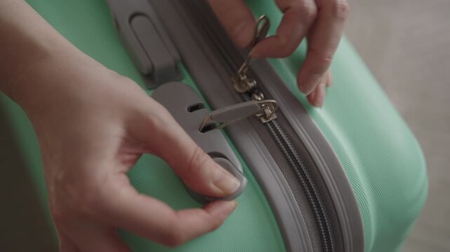 Top view of female traveler hands locking suitcase with combination lock, preparing luggage for journey, securing personal belongings for travel, tourism and vacation, close-up, slow motion.