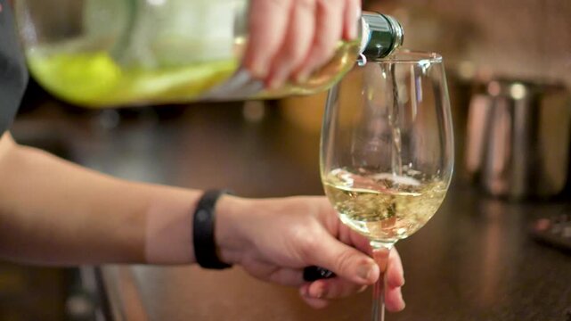 A Bartender Pours white Wine Into A Glass