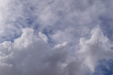 Fototapeta premium Vast, puffy white clouds drift across a clear blue expanse