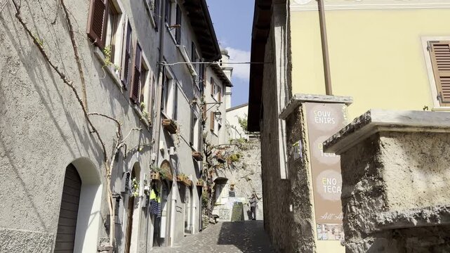 Narrow Historic Street in Limone sul Garda with Yellow Stucco Building, Church Bell Tower and Climbing Vine, Lake Garda, Italy

