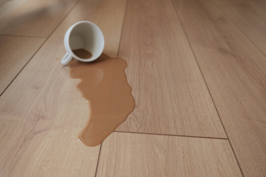 Coffee spills on wooden floor during a busy morning time