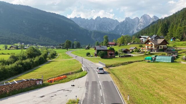 Aerial tracking shot of car driving toward Gosaukamm mountains in Gosau, Austria