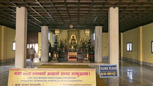 Interior of a Buddhist temple featuring a golden Buddha statue, colorful decorations, and prayer seating. Spiritual and peaceful ambiance ideal for religion, meditation, Bodh Gaya , Bihar, India