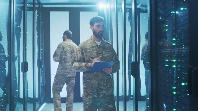 Soldier checks server system, Caucasian soldier oversees data activity in clean data center corridor