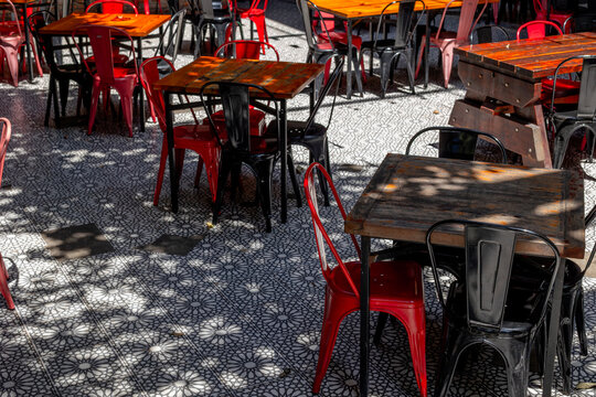 Empty outdoor cafe tables and chairs on patterned pavement