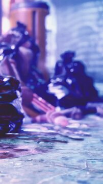 A person is sitting on the street among scattered items. The location has buildings and other urban elements in the background. The day appears cloudy with low light.