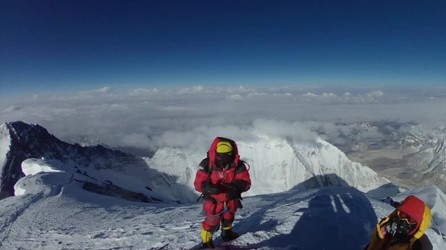 Alpinists wearing oxygen masks and down suits climb the final ridge towards the summit of Mount Everest