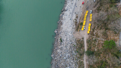 Top-down aerial view of the Ganga River in Rishikesh, Uttarakhand on a winter morning, showing calm flowing water through the Himalayan foothills. © Lucky Tony 
