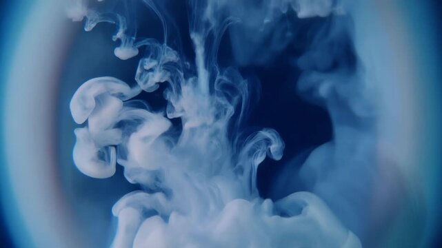 White ink or paint dissolving in dark blue water creating abstract shapes