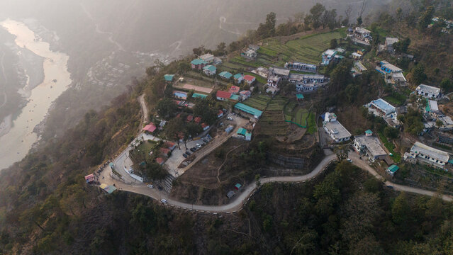 Aerial view of Kuee village in Tehri Garhwal, Uttarakhand, near Rishikesh, with the Ganga River flowing through Tota Ghati, surrounded by lower Himalayan hills and forests of sal, peepal, banyan.