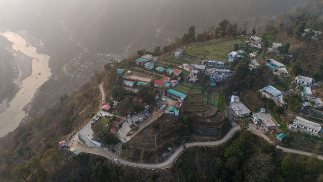 Aerial view of Kuee village in Tehri Garhwal, Uttarakhand, near Rishikesh, with the Ganga River flowing through Tota Ghati, surrounded by lower Himalayan hills and forests of sal, peepal, banyan.
