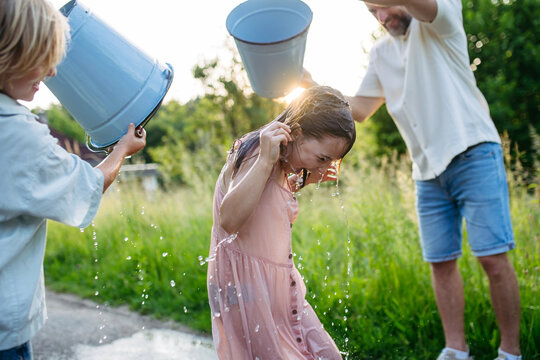 Father and son pouring water on girls during Easter Monday tradition.
