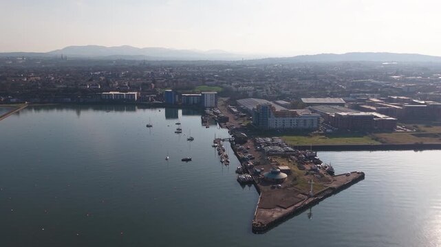 Scenic aerial view of Granton Harbour residential district and marina with sailing yachts, stone pier and coastal beach towards Edinburgh city skyline, Scotland