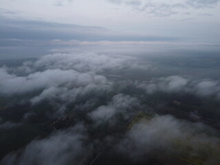 Fototapeta premium Aerial view of a landscape shrouded in mist, capturing the serene and mysterious essence of nature amidst cloudy skies.