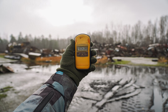 Dosimeter in hand on background museum of special equipment that helped cleaning Chernobyl nuclear power plant after explosion. Radiation sign