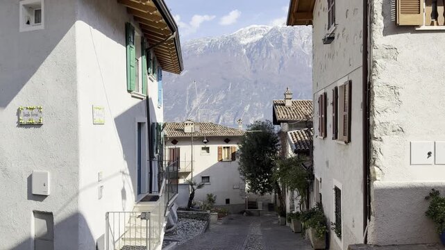 Charming Residential Alley in Limone sul Garda with Snow-Capped Mountains, White Traditional Houses and Mediterranean Vegetation, Lake Garda, Italy

