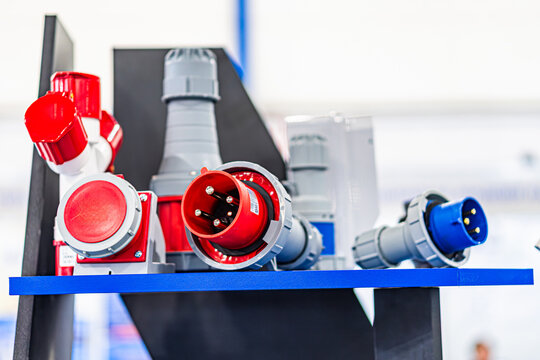 Metallic pipes and fittings of various sizes, colors gray, blue, red on a blue display shelf in an indoor setting Objects appear to be valves, elbows, straight sections, possibly a warehouse or wo