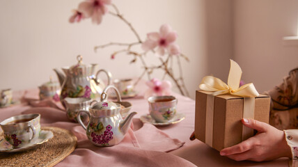 Elegant tea set with floral design and a gift box being presented