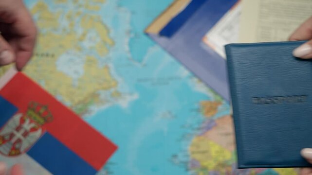Consular worker hands Serbian passport to immigrant among approved documents and global map.