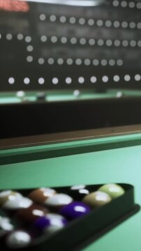 Two players concentrate on their shots while playing billiards at a local recreation center in the evening. The table is well lit and the atmosphere is lively with onlookers.