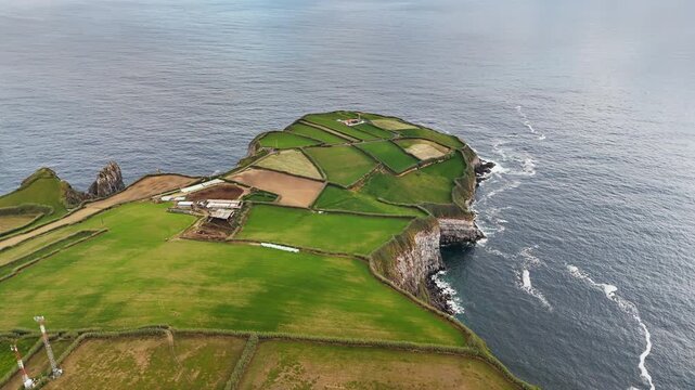 Rural patchwork fields above volcanic rocky shoreline with Atlantic Ocean, Azores. Aerial view