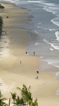 People walking at coastline of beach in Da Nang, special red flags on shore indicating high tide and dangerous strong waves, warning for tourists, safety flag symbols signaling for staying cautious.