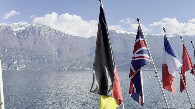 European National Flags on Promenade at Lake Garda Italy with Snow Capped Alps and Blue Lake in Background Sunny Day 4K HDR
