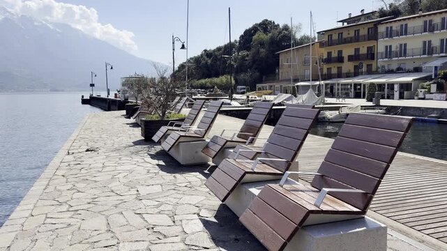 Limone sul Garda, Lake Garda, Italy, editorial, panorama, town, marina, boats, speedboat, palm trees, colorful buildings, rocky cliff, mountain, promenade, waterfront, lakeside, pier, dock, street lam