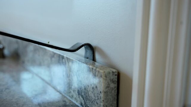 Close up view of hands working with electrical wires and outlet box during home repair installation. Worker removing old kitchen or bathroom furniture during home renovation using crowbar and hammer.