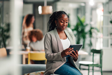 Naklejka na ściany i meble Black businesswoman using digital tablet in modern office
