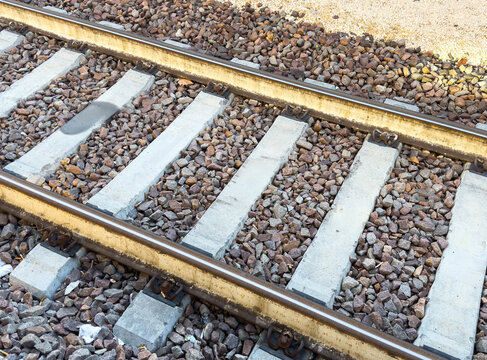 Close-up of railway tracks with gravel ballast on a sunny day