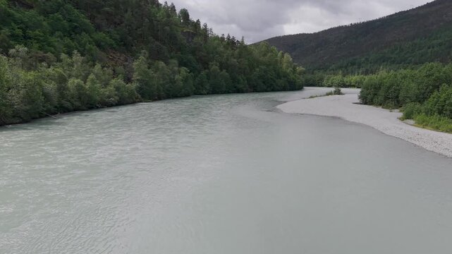 Cinematic Drohnenflug entlang eines Flusses in Norwegen. Spektakul&auml;re Berglandschaft mit dichtem Wald