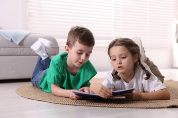 Obraz premium Cute little kids reading book on floor indoors